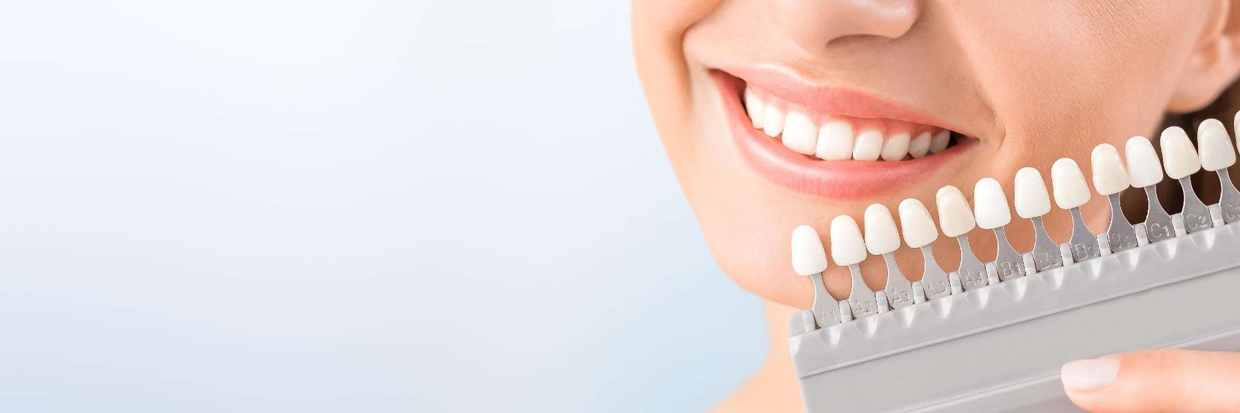 A smiling woman holding multiple shades of teeth