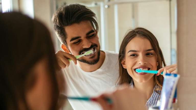 A couple brushing their teeth in the mirror | dentist Clifton Hill