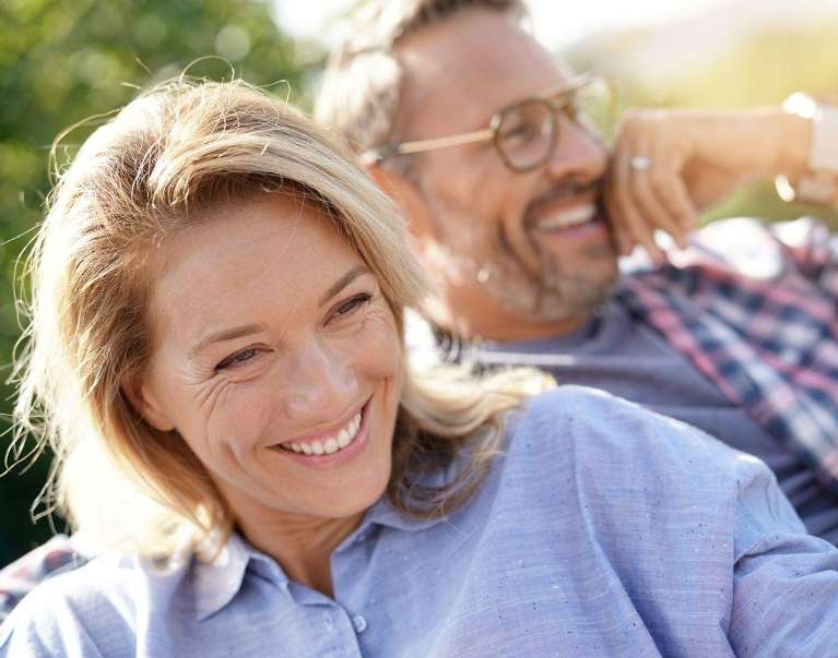 An older couple smiling outside their home
